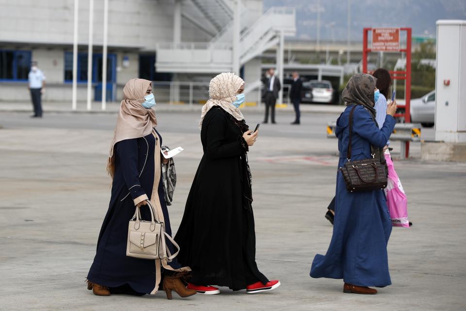 Migrants wearing face masks to prevent the spread of the coronavirus, board an airplane bound for Britain at the Eleftherios Venizelos International Airport in Athens, on Monday, May 11, 2020. Sixteen asylum-seeking minors and 34 migrants were relocated as part of a migrant reunification plan agreed between the two countries. (AP Photo/Thanassis Stavrakis)