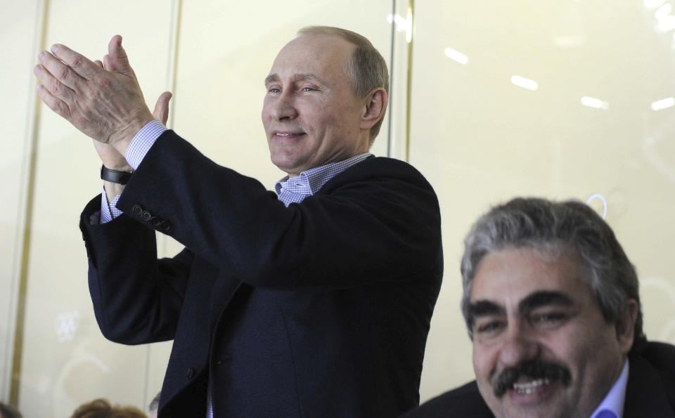 Russia's President Putin applauds as he watches the men's preliminary round ice hockey game between Russia and the U.S. at the Sochi 2014 Winter Olympic Games