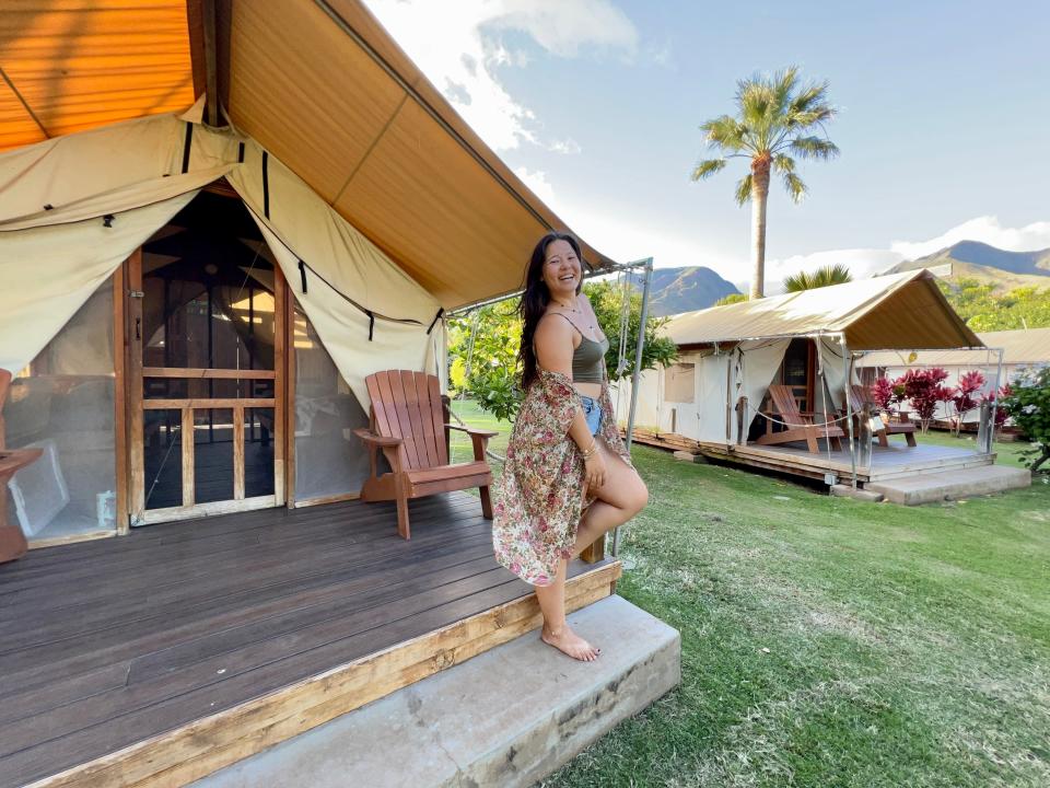 Ashley Probst posing in front of tentalow with wood deck on concrete slab, palm trees in background