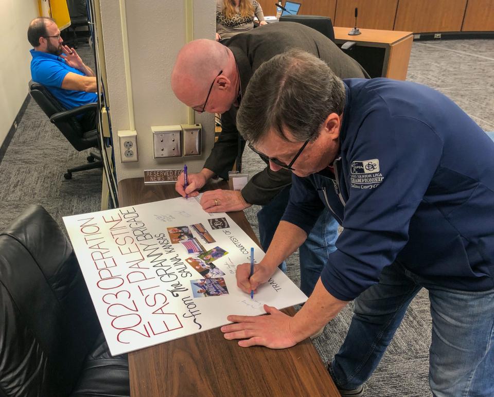 Saline County Commissioners Joe Hay and Monte Shadwick sign a poster board card that will accompany the delivery of water to East Palestine, Ohio. The county and city commissioners signed the card.