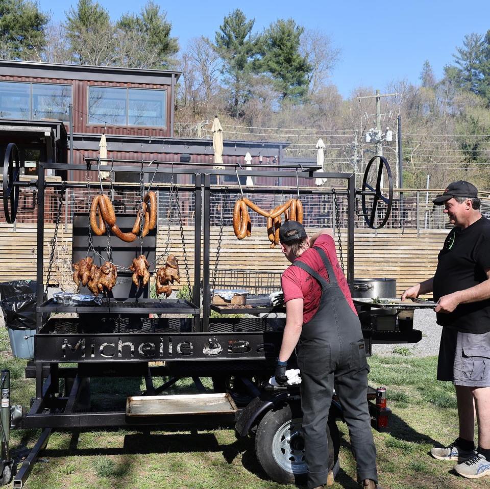 Chef Michelle Bailey cooking on an open fire on her custom wood-fired grill, "Jolene" outside of Smoky Park Supper Club in Asheville.