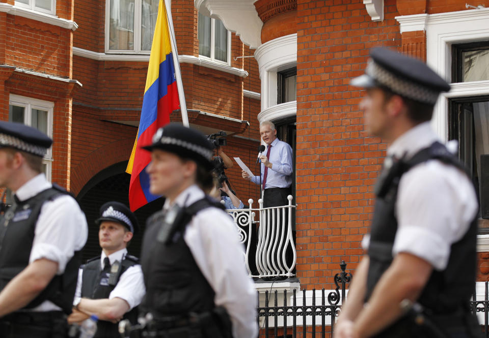 FILE - In this Aug. 19, 2012 file photo, surrounded by British police, WikiLeaks founder Julian Assange, center, makes a statement to the media and supporters from a window of the Ecuadorian Embassy in central London. Police in London arrested WikiLeaks founder Assange at the Ecuadorean embassy Thursday, April 11, 2019 for failing to surrender to the court in 2012, shortly after the South American nation revoked his asylum. (AP Photo/Sang Tan, File)