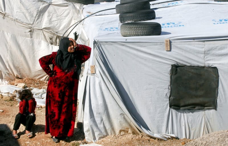 FILE PHOTO: A Syrian refugee woman stands outside a tent at a camp in Bar Elias