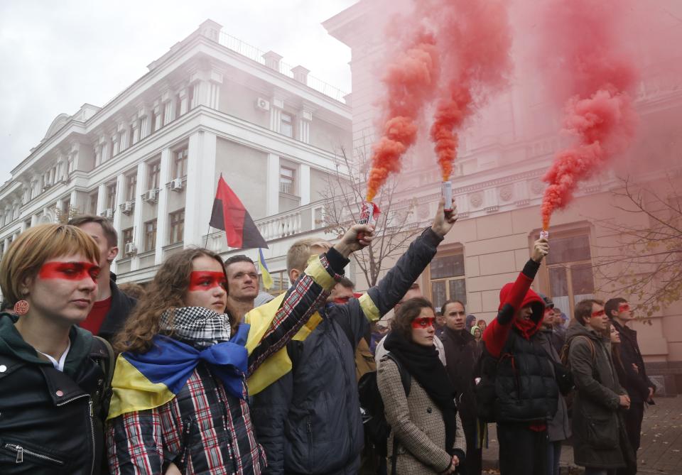 Protesters light flares during a rally near the Ukraine Presidential Administrations building in Kyiv, Ukraine, Sunday, Oct. 6, 2019. Thousands are rallying in the Ukrainian capital against the president's plan to hold a local election in the country's rebel-held east, a move seen by some as a concession to Russia. (AP Photo/Efrem Lukatsky)