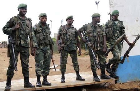 Congolese soldiers stand guard as they watch residents blocking a road as they protest the killings of two locals near Beni in North Kivu province October 22, 2014. REUTERS/Kenny Katombe