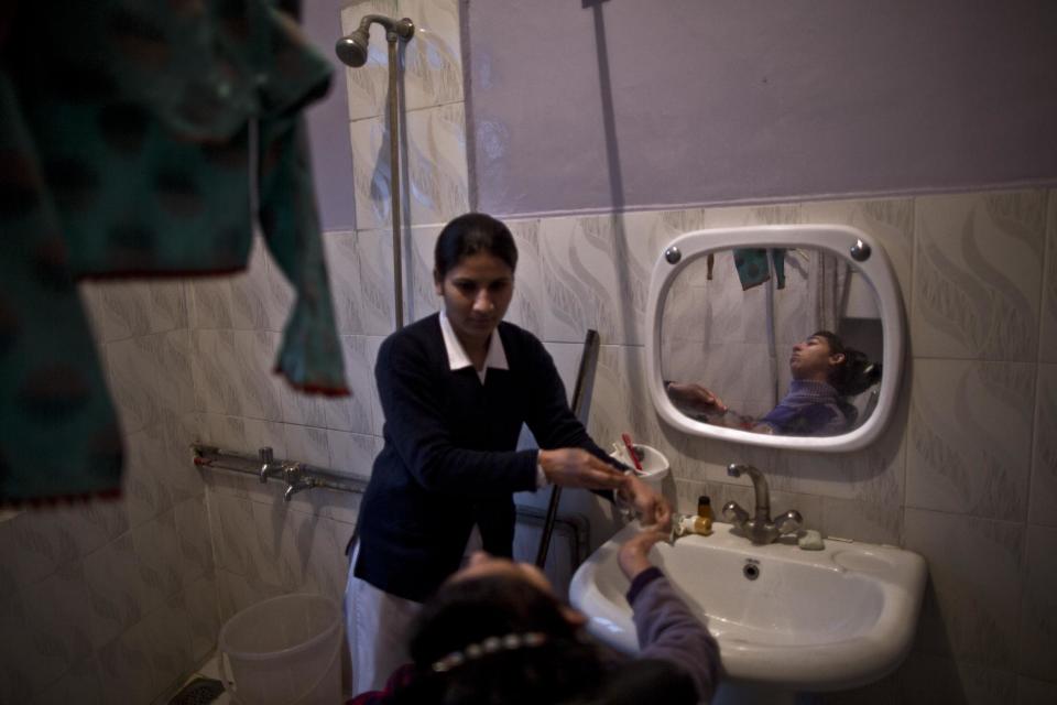 In this Sunday, Feb. 16, 2014, photo, Sonia Shawkat, 21, a Pakistani nurse, washes the hands of, Ayesha Gul Rahman, 26, a paralyzed patient, who lives at St. Joseph’s Hospice, after having her dinner, at the hospice in Rawalpindi, Pakistan. Mohammed Aqeel spent weeks at home in Pakistan waiting for death after suffering a debilitating spinal cord injury in a car crash before friends suggested he come to St. Joseph’s Hospice on the outskirts of the capital, Islamabad. Now 13 years later, his life and those of some 40 others who live on its grounds might be changed forever as this hospital of last resort faces closure over its rising debts.(AP Photo/Muhammed Muheisen)