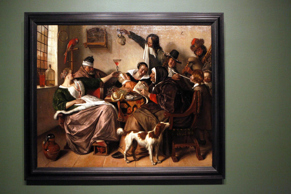 This June 19, 2013 photo shows Jan Steen's painting "As the Old Sing, So Twitter the Young" on display in the "Girl with a Pearl Earring: Dutch Paintings from the Mauritshuis" exhibit during a media preview at the museum in Atlanta. The exhibit, which opens Sunday and runs through Sept. 29, includes Johannes Vermeer’s famous “Girl With a Pearl Earring" painting and 34 other works from the Dutch Golden Age. (AP Photo/Jaime Henry-White)