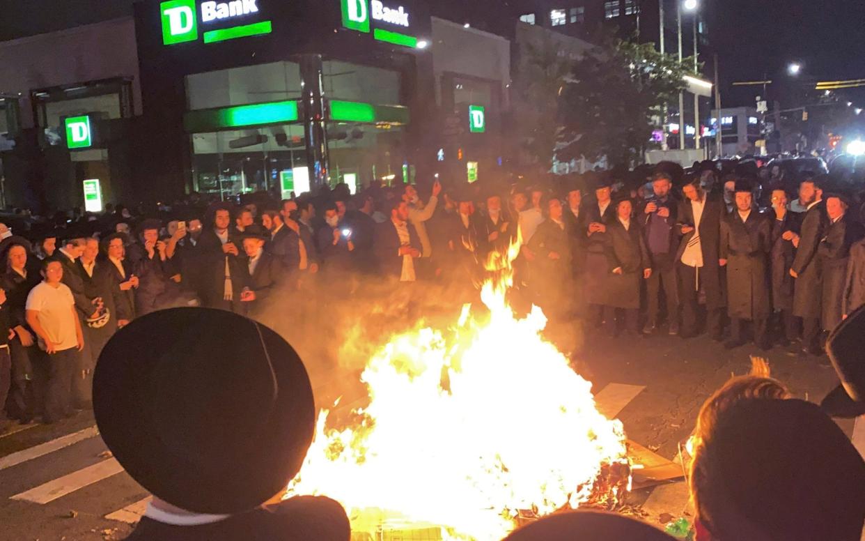 Members of the Orthodox Jewish community surround a rubbish fire in the street, - Joe Marino/New York Post