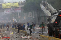 Student protesters use sticks to attack riot police during clash at a outside parliament in Jakarta, Indonesia, Tuesday, Sept. 24, 2019. Thousands of students have staged rallies across Indonesia against new law that considered has crippled means in fighting the country's endemic corruption. (AP Photo/Tatan Syuflana)