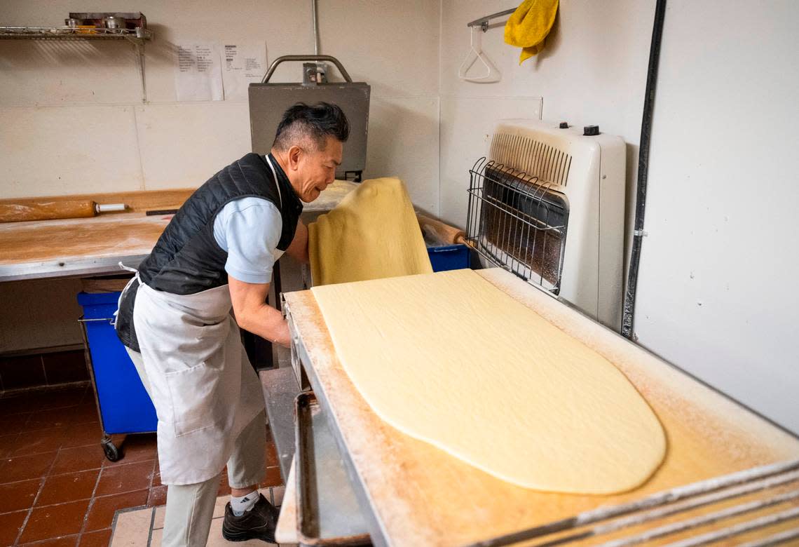 Yam grabs a 6-foot slab off of a dough sheeter, a machine that flattens the dough. On the workbench behind him, he will then cut each doughnut by hand, a process he repeats dozens of times from 10 p.m. to 8 a.m. the next morning.