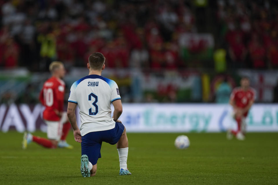 England's Luke Shaw knees along Wales players, background, just before the kick off of the World Cup group B soccer match between England and Wales, at the Ahmad Bin Ali Stadium in Al Rayyan , Qatar, Tuesday, Nov. 29, 2022. (AP Photo/Frank Augstein)