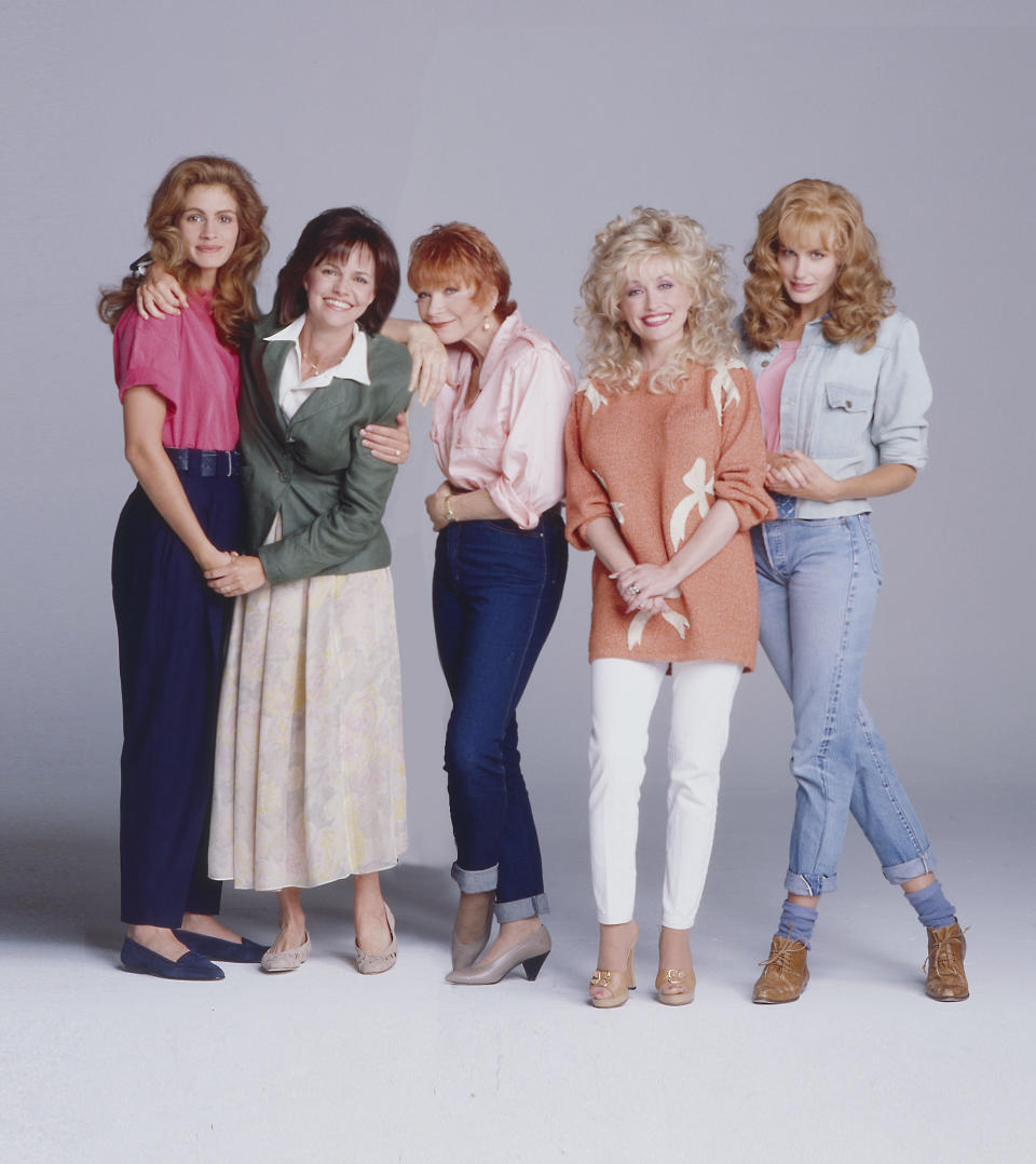 Julia Roberts, Sally Field, Dolly Parton, Daryl Hannah, and Shirley MacLaine posing together, each wearing casual and stylish outfits