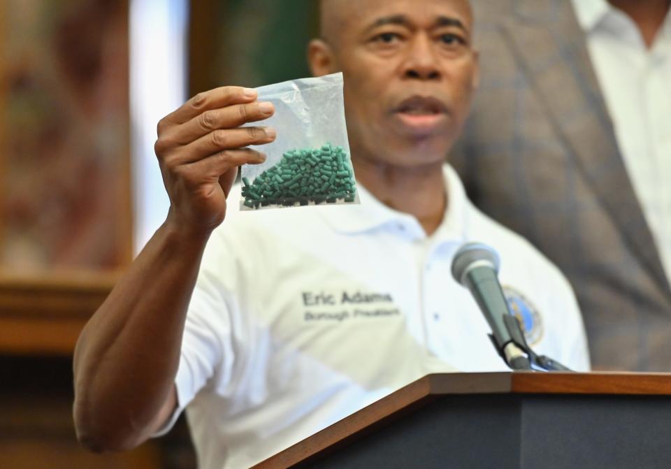 A man holds a bag of green pellets.