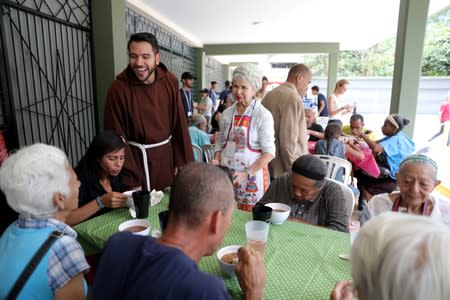 Venezuelan priest Luis Antonio Salazar talks to local residents as they receive a charity lunch at Chiquinquira Catholic church in Caracas