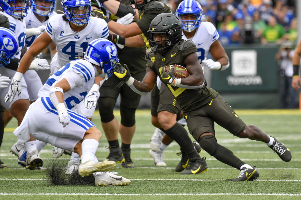 Oregon running back Mar'Keise Irving makes a cut as he rushes against BYU defensive back Ammon Hannemann and linebacker Keenan Pili during the first half of an NCAA college football game, Saturday, Sept. 17, 2022, in Eugene, Ore. (AP Photo/Andy Nelson)