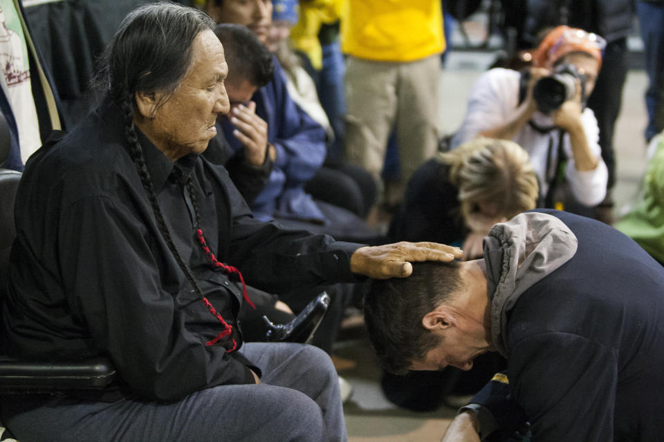 Leonard Crow Dog, a Lakota elder and highly-regarded activist, left, places his hand over Wesley Clark Jr.'s head during a forgiveness ceremony for veterans at the Four Prairie Knights Casino &amp; Resort on the Standing Rock Sioux Reservation on Monday.