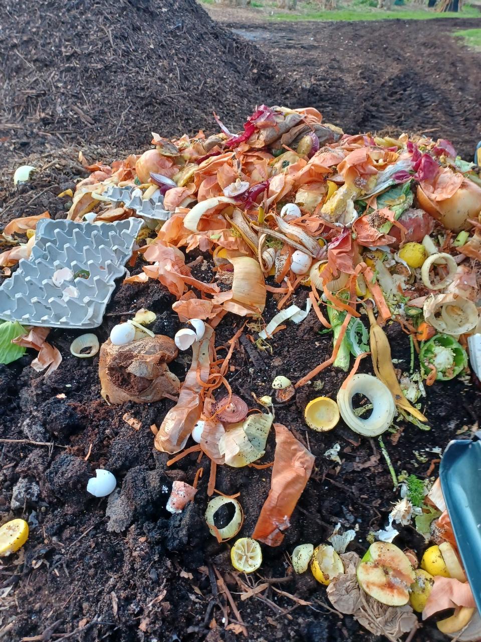 Raw food scraps and other recyclables being added to an existing compost pile at Compost Community.