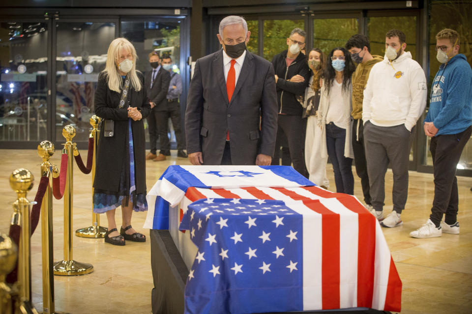 Israeli Prime Minister Benjamin Netanyahu stands before the casket of Sheldon Adelson upon arrival to Ben Gurion Airport, near the city of Lod, Israel, Thursday, Jan. 14, 2021. Adelson's family, including his wife, Miriam, at left, are present. Adelson, the billionaire mogul and power broker who built a casino empire spanning from Las Vegas to China and became a singular force in domestic and international politics has died after a long illness, his wife said Tuesday, Jan. 12, 2021. (Ami Shooman, Israel Hayom/ Pool Photo via AP)