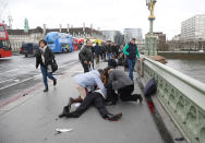 <p>People assited several injured victims on Westminster Bridge after a car mowed over many in London on 22 March 2017. [Toby Melville | Reuters] </p>