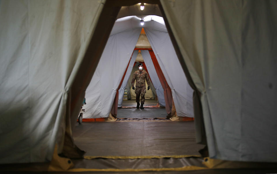 An Italian soldier walks inside the field hospital built in Crema, Italy, Tuesday, March 24, 2020. Cuba has sent a medical brigade to Italy to help treat coronavirus patients in the field hospital that was set up in Crema, one of Northern Italy's areas most hit by the virus. For most people, the new coronavirus causes only mild or moderate symptoms. For some it can cause more severe illness, especially in older adults and people with existing health problems. (AP Photo/Antonio Calanni)