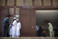 People stand at the entrance to the Kowloon Mosque a day after it was sprayed with blue-dyed water by a police riot-control vehicle in Hong Kong, Monday, Oct. 21, 2019. Hong Kong officials apologized to leaders of a mosque after riot police sprayed the building's gate and some people nearby with a water cannon as they tried to contain pro-democracy demonstrations. (AP Photo/Mark Schiefelbein)