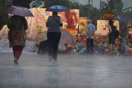 People lay flowers and well-wishes for former Singaporean prime minister Lee Kuan Yew in a heavy downpour at the Singapore General Hospital in Singapore March 22, 2015. REUTERS/Edgar Su