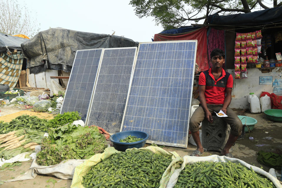 An Indian shopkeeper sits near solar panels placed outside his stall in a temporary settlement along the Yamuna river in New Delhi, on World Sustainable Energy Day, June 22, 2022. / Credit: Pankaj Nangia/Anadolu Agency/Getty