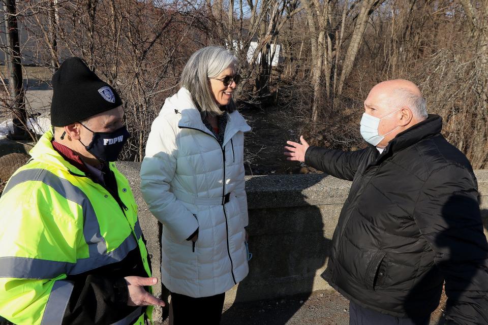 U.S. Rep. Katherine Clark, D-Mass., speaks with Framingham Mayor Charlie Sisitsky, right, and Simon Alexandrovich, director of transportation engineering for the city, on the School Street Bridge over the Cochituate Brook, Jan 24, 2022.