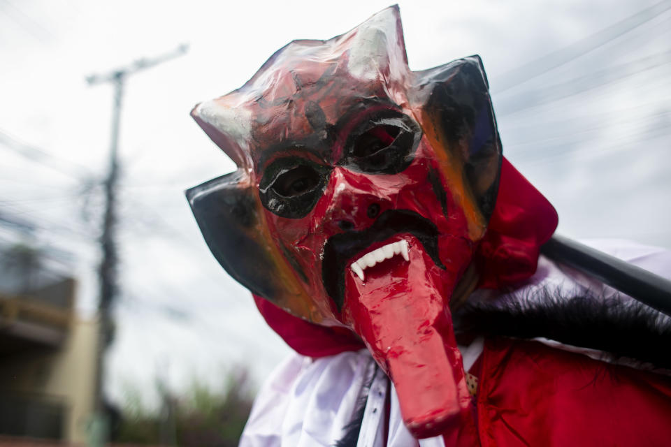 A member of a “bate-bola” or ball hitters group - men who dress up in exuberant, identical, hand-made costumes known as “fantasias” - makes a brief appearance as part of a Carnival tradition despite restrictions due to the new coronavirus pandemic, in Rio de Janeiro, Brazil, Saturday, Feb. 13, 2021. Rio’s city government officially suspended Carnival and warns it will have no tolerance for those who try to celebrate with open street parades or clandestine parties. (AP Photo/Bruna Prado)