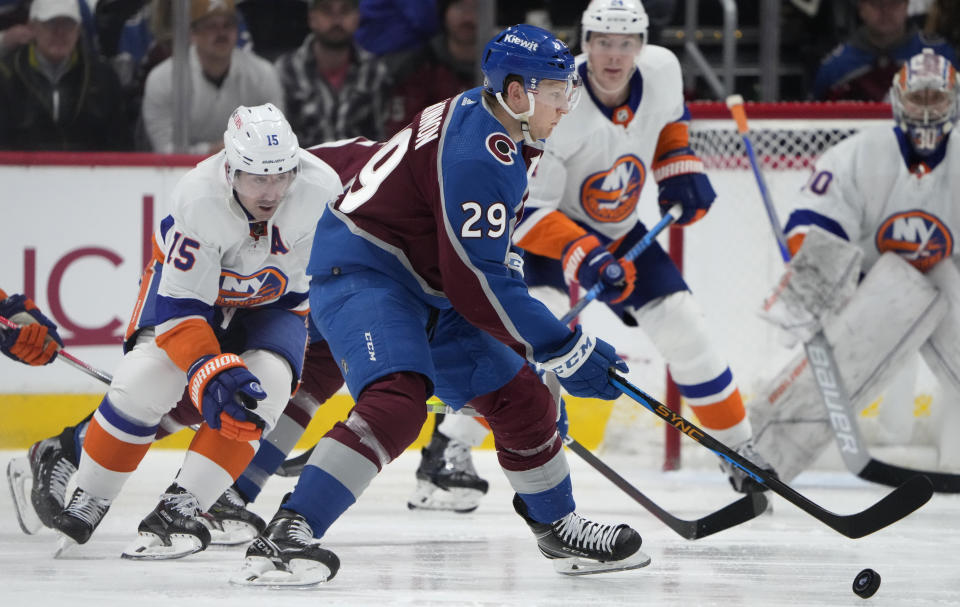 Colorado Avalanche center Nathan MacKinnon, right, collects the puck as New York Islanders right wing Cal Clutterbuck defends in the second period of an NHL hockey game Tuesday, Jan. 2, 2024, in Denver. (AP Photo/David Zalubowski)