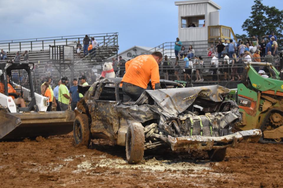 Aaron Crane inspects what's left of his 1976 Chrysler Cordoba after the engine caught fire during the 2022 Monroe County Fair Demolition Derby.