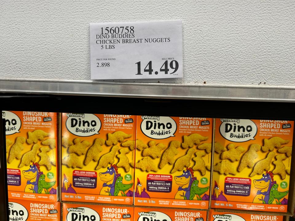 dinosaur nuggets in orange boxes on display at a costco with a 14.49 price sign above them on wall