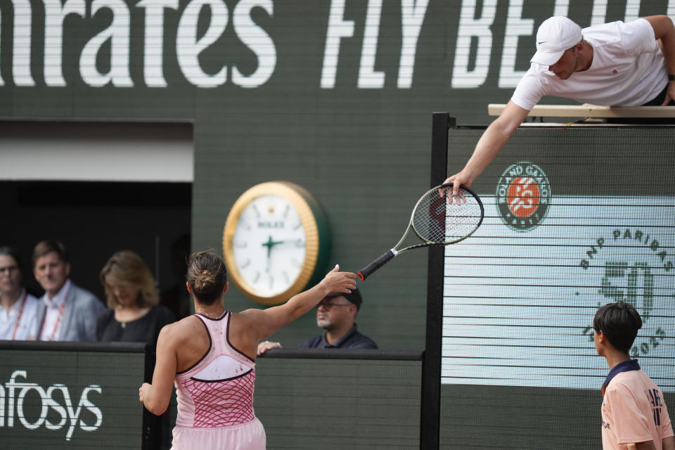 Aryna Sabalenka of Belarus gets a new racket from the player's box in the third set of the semifinal match of the French Open tennis tournament against Karolina Muchova of the Czech Republic at the Roland Garros stadium in Paris, Thursday, June 8, 2023. (AP Photo/Thibault Camus)