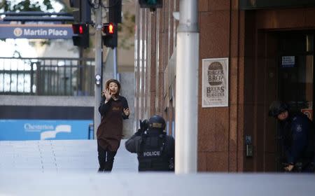 A hostage runs towards a police officer outside Lindt cafe, where other hostages are being held, in Martin Place in central Sydney December 15, 2014. REUTERS/Jason Reed