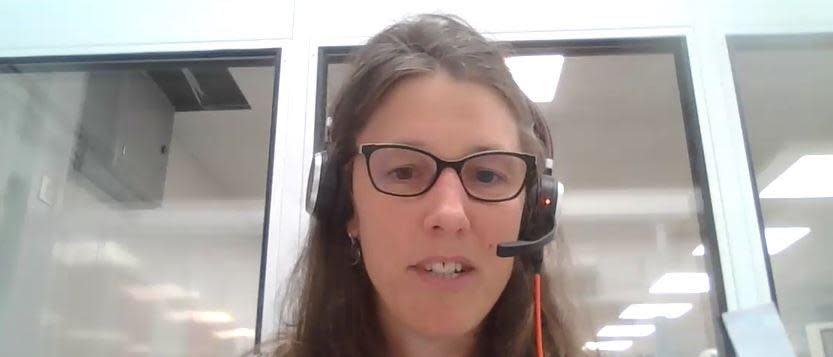 A woman with long hair and glasses wearing a headset