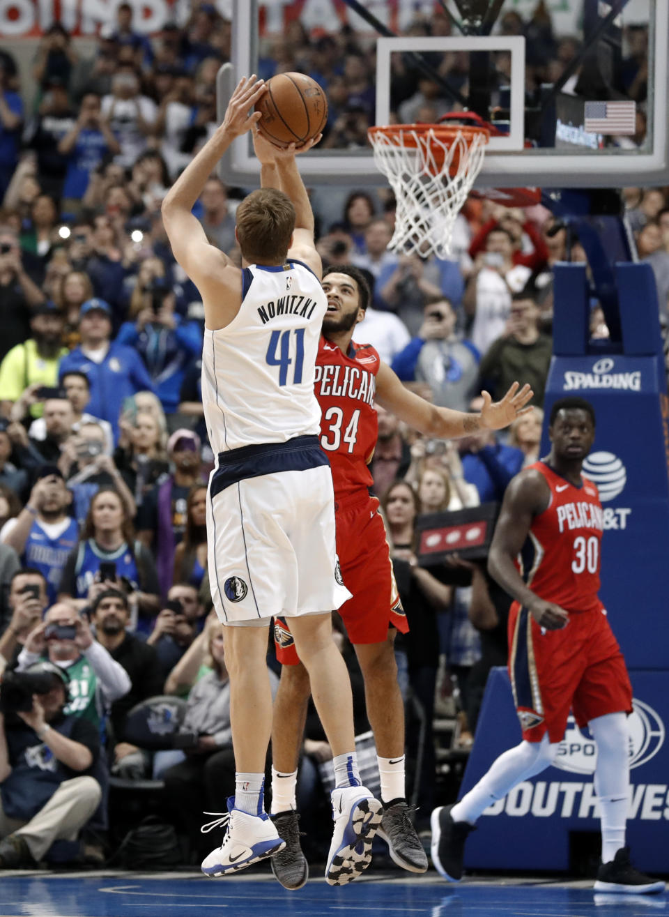 Dallas Mavericks forward Dirk Nowitzki (41) shoots as New Orleans Pelicans' Kenrich Williams (3) defends and Pelicans' Julius Randle (30) and Anthony Davis (23) watch in the first half of an NBA basketball game in Dallas, Monday, March 18, 2019. With the basket, Nowitzki became the NBA's sixth-leading scorer. (AP Photo/Tony Gutierrez)