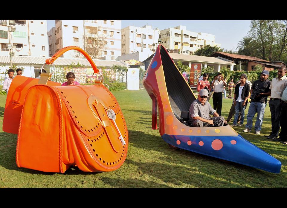 Indian wacky car designer Sudhakar Yadav sits inside a vehicle made in the shape of a stilletto shoe (R), next to another vehicle made in the shape of a ladies hand bag.