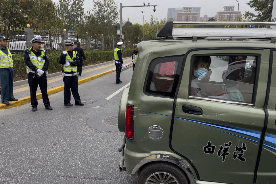 A woman looks out from a tricycle cart after policemen blocked the roads near the Babaoshan Revolutionary Cemetery in Beijing Thursday, Nov. 2, 2023. Hundreds, possibly thousands, of people gathered near a state funeral home Thursday as former Premier Li Keqiang was being put to rest. (AP Photo/Andy Wong)