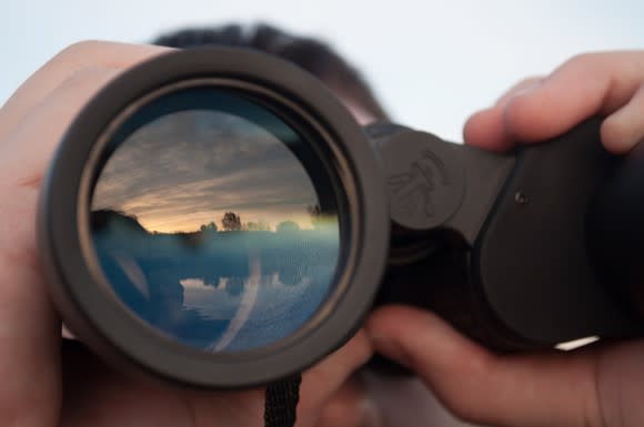 A man using binoculars to look off into the distance.