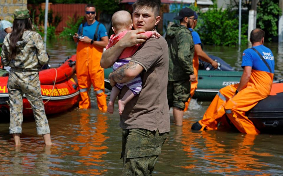 A man carries a child as members of Russia's emergencies ministry evacuate residents of a flooded area - ALEXANDER ERMOCHENKO/REUTERS
