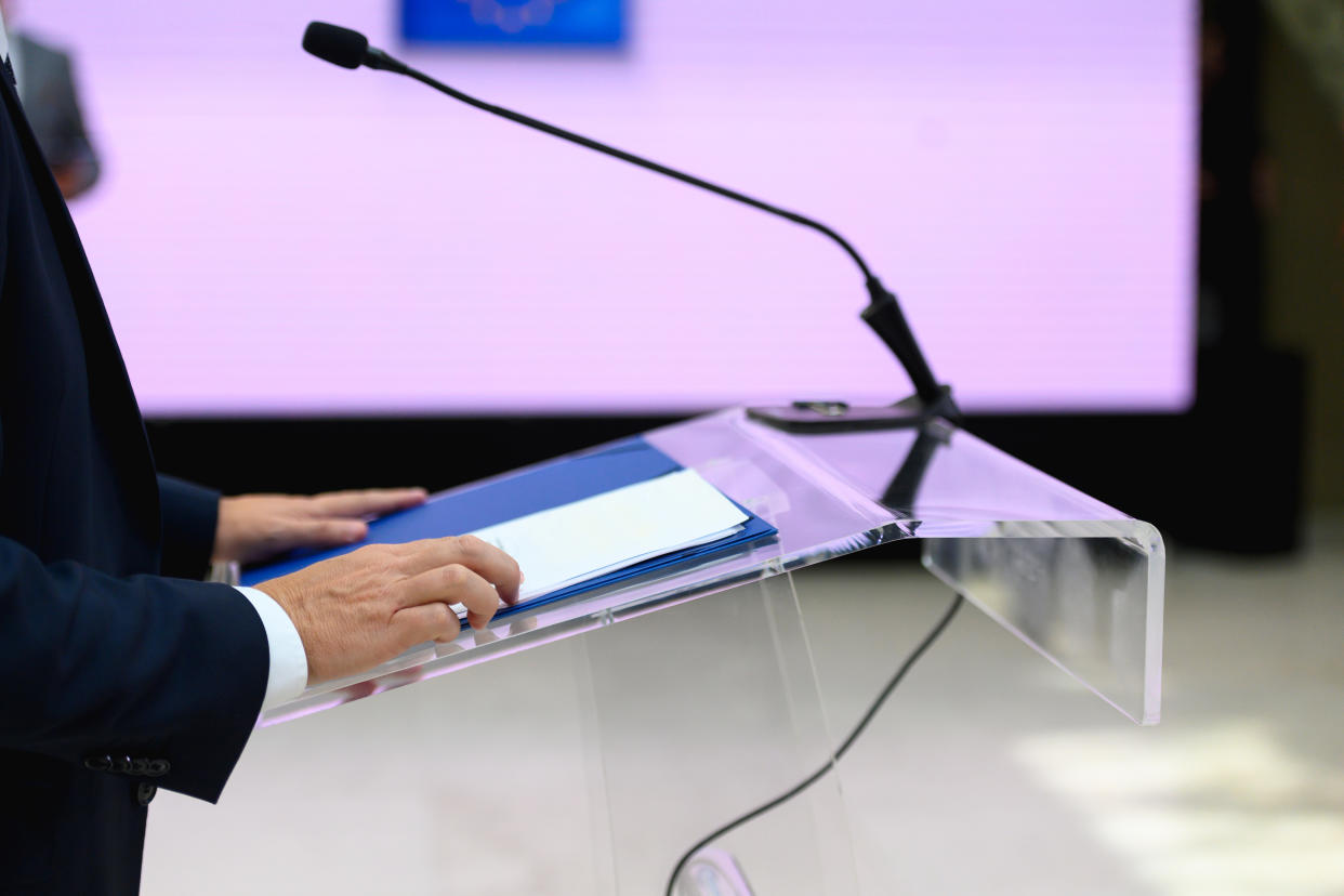 A person's hands on a podium at a political debate.