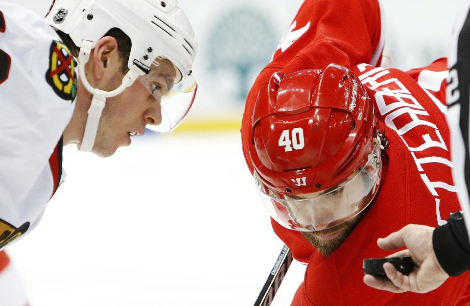 Chicago Blackhawks center Jonathan Toews, left, and Detroit Red Wings left wing Henrik Zetterberg (40), of Sweden, eye the puck on a face off in the second period of an NHL hockey game Wednesday, Jan. 22, 2014, in Detroit. (AP Photo/Paul Sancya)