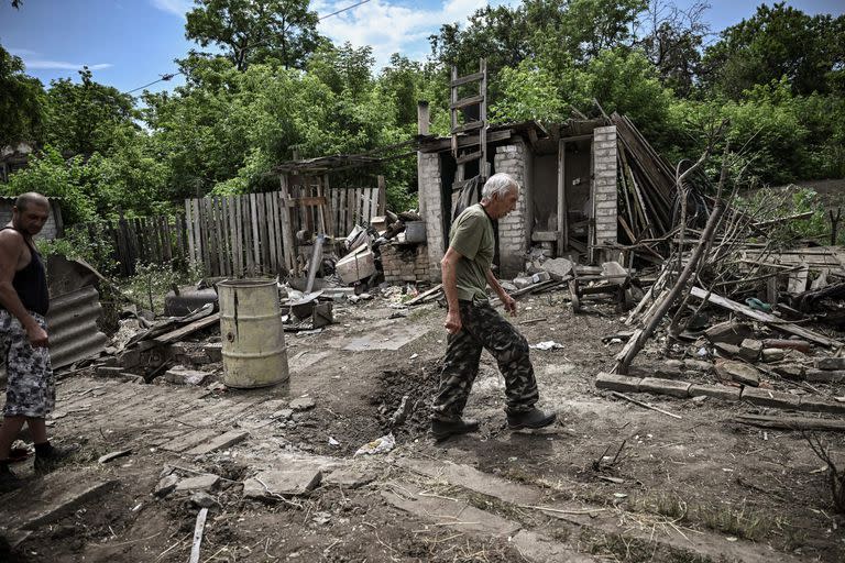 Un hombre camina por el patio de una casa dañada tras un bombardeo en el que murieron dos personas en la ciudad de Lysychansk , en la región oriental ucraniana de Donbass, el 13 de junio de 2022, en medio de la invasión rusa de Ucrania.