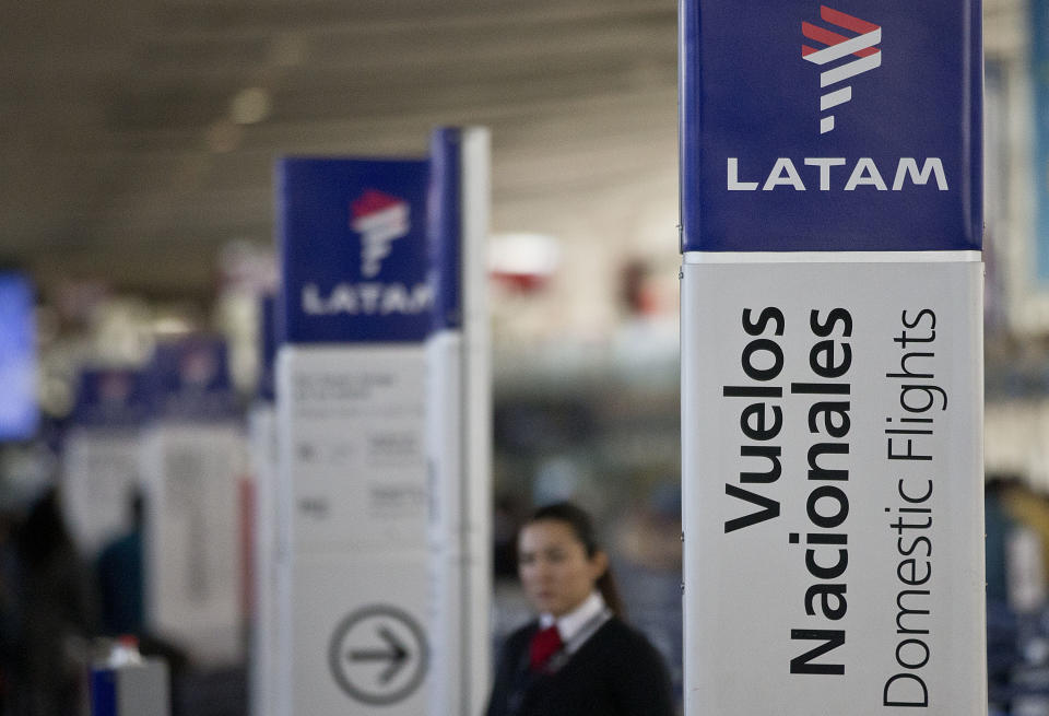 FILE - In this July 25, 2016, file photo, an agent of LATAM airlines stands by the counters at the airport in Santiago, Chile. The South American carrier said Tuesday, May 26, 2020, it is seeking Chapter 11 bankruptcy protection as it grapples with the sharp downturn in air travel sparked by the coronavirus pandemic. (AP Photo/Esteban Felix, File)