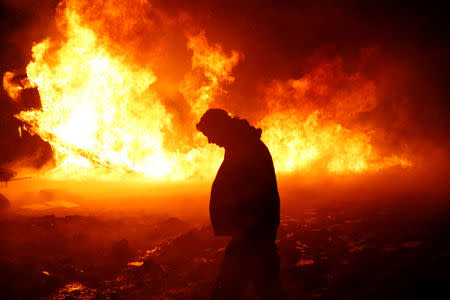 Chanse Zavalla, 26, from California, walks past a building set alight by protesters preparing to evacuate the main opposition camp against the Dakota Access oil pipeline near Cannon Ball North Dakota, U.S., February 22, 2017. REUTERS/Terray Sylvester