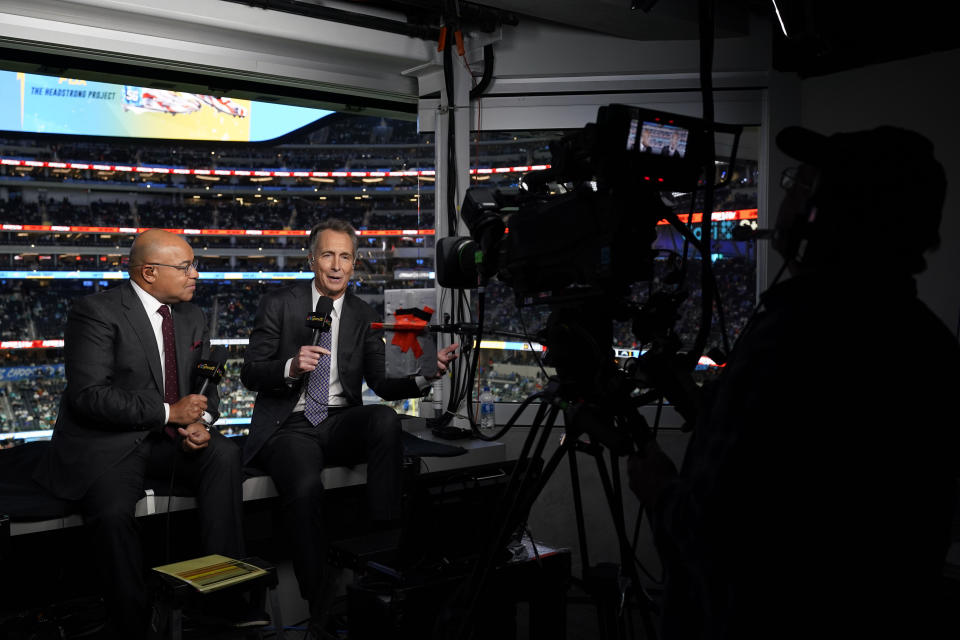 NBC Sports play-by-play announcer Mike Tirico, left, sits next to color commentator Cris Collinsworth before an NFL football game between the Los Angeles Chargers and the Miami Dolphins on Dec. 11, 2022, in Inglewood, Calif. (AP Photo/Jae C. Hong)