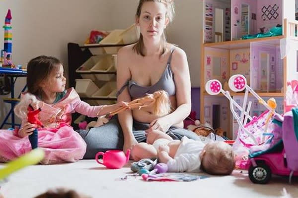 Kathy, exhausta y con la mirada ausente, posa con sus dos hijos en el suelo de una habitación llena de juguetes desordenados. (Foto: Facebook)