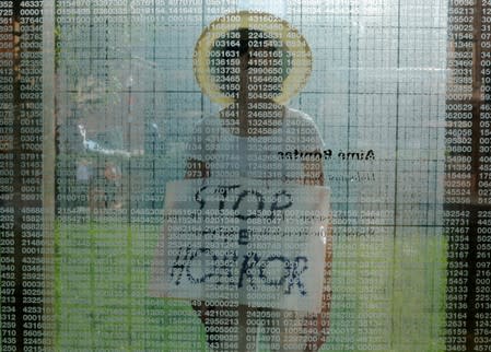 Doris Tennant walks through the Holocaust Memorial carrying a sign reading "Stop the Horror" in Boston