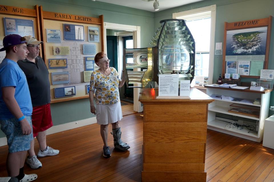 Docent Ellie Chase shows off the beehive-shaped Fresnel lens that was used in the lighthouse until 1991, when it was replaced by a rotating beacon.