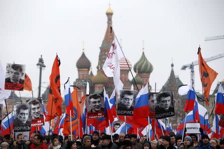 People hold flags and posters during a march to commemorate Kremlin critic Boris Nemtsov, who was shot dead on Friday night, near St. Basil's Cathedral in central Moscow March 1, 2015. REUTERS/Sergei Karpukhin
